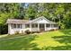 Inviting single-story home featuring a white brick exterior, a cozy front porch, and lush landscaping at 3999 Phils Ct, Tucker, GA 30084