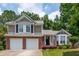 Charming two-story home featuring a two-car garage, a landscaped yard, and a welcoming front porch with an American flag at 1115 Manor Nw Way, Kennesaw, GA 30144