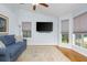 Living room with a comfortable blue sofa, a ceiling fan, hardwood floors, and natural light from the large windows at 1115 Manor Nw Way, Kennesaw, GA 30144
