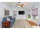 Cozy living room with a comfortable blue sofa, a ceiling fan, hardwood floors, and natural light from the large windows at 1115 Manor Nw Way, Kennesaw, GA 30144