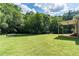 Green backyard featuring a spacious lawn, lush trees, and a covered patio, offering ample space at 5670 Lanny Dr, Powder Springs, GA 30127