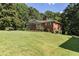 View of a brick home with a lush green lawn and mature trees at 5670 Lanny Dr, Powder Springs, GA 30127