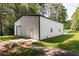 Large metal garage with an access door and a roll-up door set on a concrete drive with ample green space at 5670 Lanny Dr, Powder Springs, GA 30127