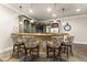 Entertaining bar with stone accents, custom cabinetry, unique pendant lighting, and four comfortable chairs at 5507 Aviemore Ct, Suwanee, GA 30024