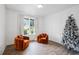 Elegant living room with hardwood floors, designer chairs, large window, and a decorative Christmas tree at 5394 Pebblebrook Se Ln, Mableton, GA 30126