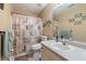 Neutral bathroom features a vanity sink, toilet, and shower with a patterned shower curtain at 15 Fairwoods Ct, Covington, GA 30016
