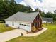 Angle view of a brick house with an attached garage, lush lawn, and mature trees, set back for privacy at 15 Fairwoods Ct, Covington, GA 30016