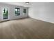 Spacious living room with neutral walls, plush carpet, multiple windows, and a door to the porch at 324 Stoney Hollow Rd, Canton, GA 30114
