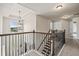 Upstairs hallway with decorative pendant lighting, wood and iron railing, and neutral carpet flooring at 538 Mulberry Fern Dr, Auburn, GA 30011