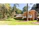 Expansive brick home exterior featuring a large deck overlooking a lush, green backyard surrounded by mature trees at 504 Milligan Dr, Stone Mountain, GA 30083
