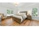 Bright main bedroom features hardwood floors, a tray ceiling, a comfortable seating area, and lots of natural light at 312 Laurel Run Cv, Sugar Hill, GA 30518