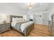 Main bedroom with hardwood floors, a tray ceiling with modern light fixture, and a view of the en suite bathroom at 312 Laurel Run Cv, Sugar Hill, GA 30518