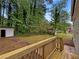 Backyard with a wooden deck, green lawn, mature trees, and a storage shed at 8272 Magnolia Dr, Jonesboro, GA 30238