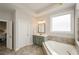 Bright bathroom featuring a large soaking tub, tiled floors, and a vanity with drawers at 2535 Castlerock Ct, Cumming, GA 30041