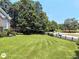 Expansive lawn features privacy fence, mature trees, and a view of a two-story brick home at 1292 Hidden Spirit Trl, Lawrenceville, GA 30045