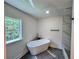 Bright bathroom featuring modern tub, grey tile floors, and natural light at 6751 Davidson Ct, Lithonia, GA 30058