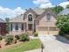 Charming brick home featuring a well-kept lawn, blooming rose bushes, and attached two-car garage, perfect for families at 2002 Ivy Ridge Se Rd, Smyrna, GA 30080