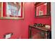 Chic powder room with a striking red wall, decorative mirror, and unique vanity for a touch of elegance at 2002 Ivy Ridge Se Rd, Smyrna, GA 30080