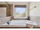 Relaxing bathroom showcases a large soaking tub with tile surround, a window, and fresh towels at 4465 Saint Andrews Crest Dr, Cumming, GA 30040