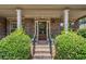 Inviting front porch with brick columns, a glass paneled door, and lush green bushes at 4465 Saint Andrews Crest Dr, Cumming, GA 30040
