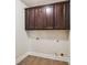 Laundry room with dark wood cabinets above a tiled floor, and hookups at 4465 Saint Andrews Crest Dr, Cumming, GA 30040