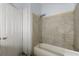 Full bathroom with tiled walls, a bathtub, shower head, and storage shelves behind the door at 1321 Mcclelland Ave, Atlanta, GA 30344