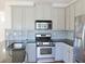 A kitchen featuring stainless steel appliances, grey cabinets, and a blue-grey backsplash at 3761 Lake Point Blvd, Suwanee, GA 30024