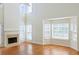Sunlit living space featuring a fireplace, hardwood floors, high ceilings, and large windows for natural light at 3761 Lake Point Blvd, Suwanee, GA 30024