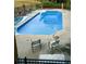 A sunny in-ground pool features a patio area, chairs, and is surrounded by a black metal fence at 604 Clearwater Ct, Mcdonough, GA 30252