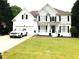 Charming two-story home featuring a well-manicured lawn, black shuttered windows, and a car parked in the driveway at 6265 Lake Windsor Pkwy, Buford, GA 30518