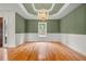 Formal dining room with green walls, wainscoting, hardwood floors, and a decorative chandelier at 8160 Stone Hill Rd, Cumming, GA 30028
