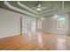 Spacious bedroom featuring hardwood floors, a decorative tray ceiling, and lots of natural light from the large windows at 8160 Stone Hill Rd, Cumming, GA 30028