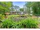 Back exterior of home featuring multiple large windows, a deck, lush grass, and stone gardens at 312 Flat Shoals Church Rd, Stockbridge, GA 30281