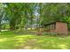 Spacious backyard with a shed featuring a porch, complemented by lush greenery and mature trees at 312 Flat Shoals Church Rd, Stockbridge, GA 30281