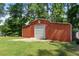 Exterior view of a red barn with a white garage door and concrete slab at 312 Flat Shoals Church Rd, Stockbridge, GA 30281
