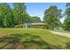 A lush green lawn surrounds the home, trees frame the front, with water visible to the right at 312 Flat Shoals Church Rd, Stockbridge, GA 30281