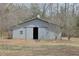 A metal barn with a sliding door in a grassy field surrounded by bare trees at 75 Price Dr, Locust Grove, GA 30248