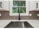 Stylish kitchen sink features modern faucet, stainless steel basin, quartz countertops, and subway tile backsplash at 975 Memory Ln, Lawrenceville, GA 30044