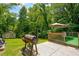 Backyard with a patio, seating area, barbecue grill, and storage shed in lush greenery at 174 Rivertown Rd, Fairburn, GA 30213