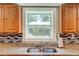 Close-up of a kitchen sink and tile backsplash by a window with natural light at 174 Rivertown Rd, Fairburn, GA 30213