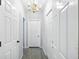 Bright hallway featuring gray flooring, a modern chandelier, and white paneled doors at 4076 Whistler Dr, Douglasville, GA 30135