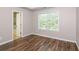 Well-lit bedroom showcases wood-look floors, a bright window with blinds, and ensuite bathroom access at 11768 Wellsley Way, Johns Creek, GA 30005