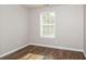 This bright bedroom features wood-look floors, fresh neutral paint, and a window providing natural light at 11768 Wellsley Way, Johns Creek, GA 30005