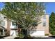 Brick townhouse featuring a two-car garage, well-maintained landscaping, and shuttered windows at 11768 Wellsley Way, Johns Creek, GA 30005
