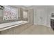 A soaking tub with tile surround, a large window, and glass shower are bathroom highlights at 2740 Longacre Park Way, Lawrenceville, GA 30044