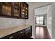 A convenient butler pantry features granite countertops, cabinetry, and subway tile backsplash at 2740 Longacre Park Way, Lawrenceville, GA 30044