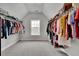 A walk-in closet with hanging rods on each side and a window for natural light at 2740 Longacre Park Way, Lawrenceville, GA 30044