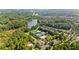 Aerial view of community with mature trees, a lake, community pool, clubhouse and tennis courts at 207 Harmony Lake Dr, Canton, GA 30115