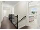 Upstairs hallway featuring wood floors, dark railing, and doorway to a bedroom with natural light at 1620 Brook Ivy Dr, Lawrenceville, GA 30044