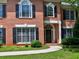Close-up of a brick home featuring an arched doorway, manicured bushes, and black shutters at 4221 Bretdale Nw Run, Kennesaw, GA 30152